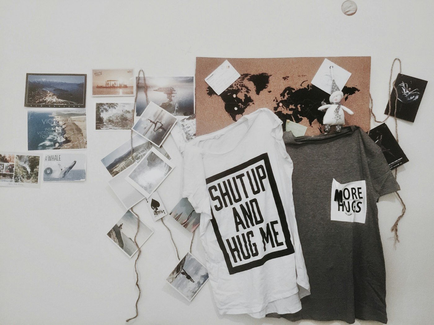 Graphic t-shirts hanging on a wall of postcards